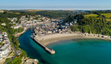 Aerial view of Looe including the beach, harbour and sea on a sunny, blue sky day