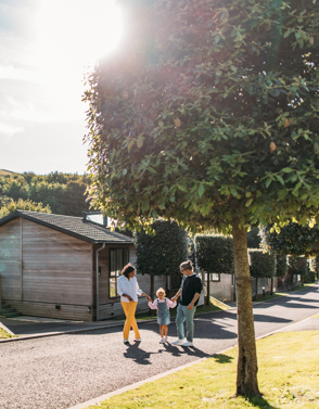 Family walking down treeline lane surrounded by lodges