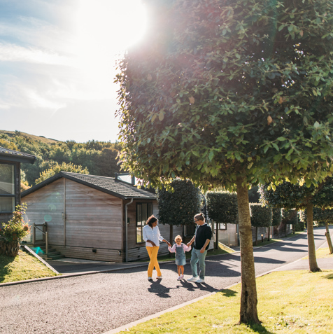 Family walking down treeline lane surrounded by lodges