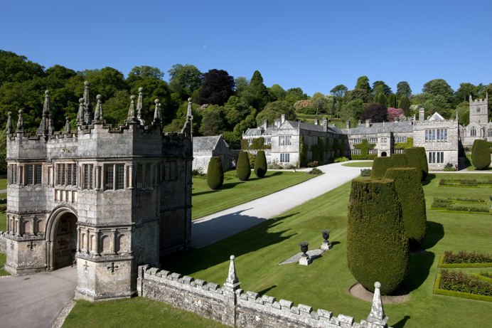 A grand national trust house and maintained gardens among surrounding woodland