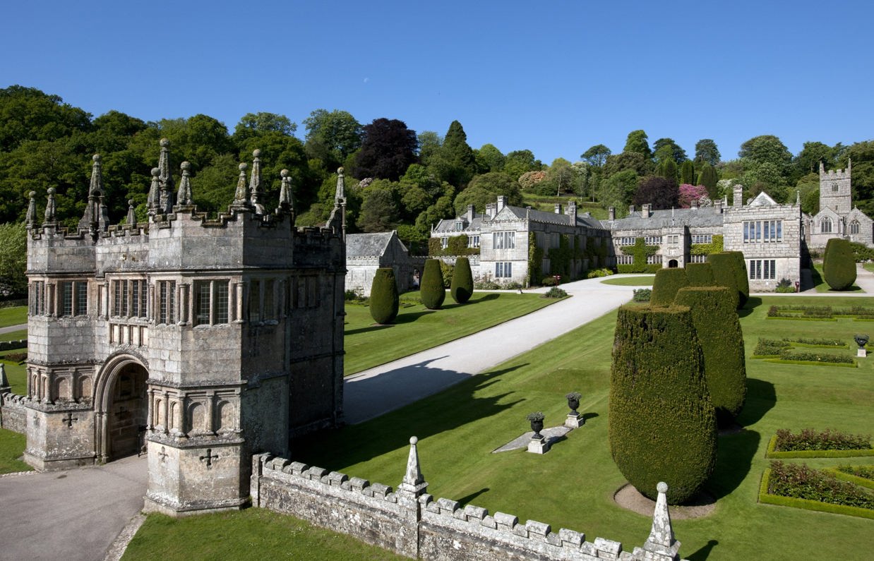 A grand national trust house and maintained gardens among surrounding woodland