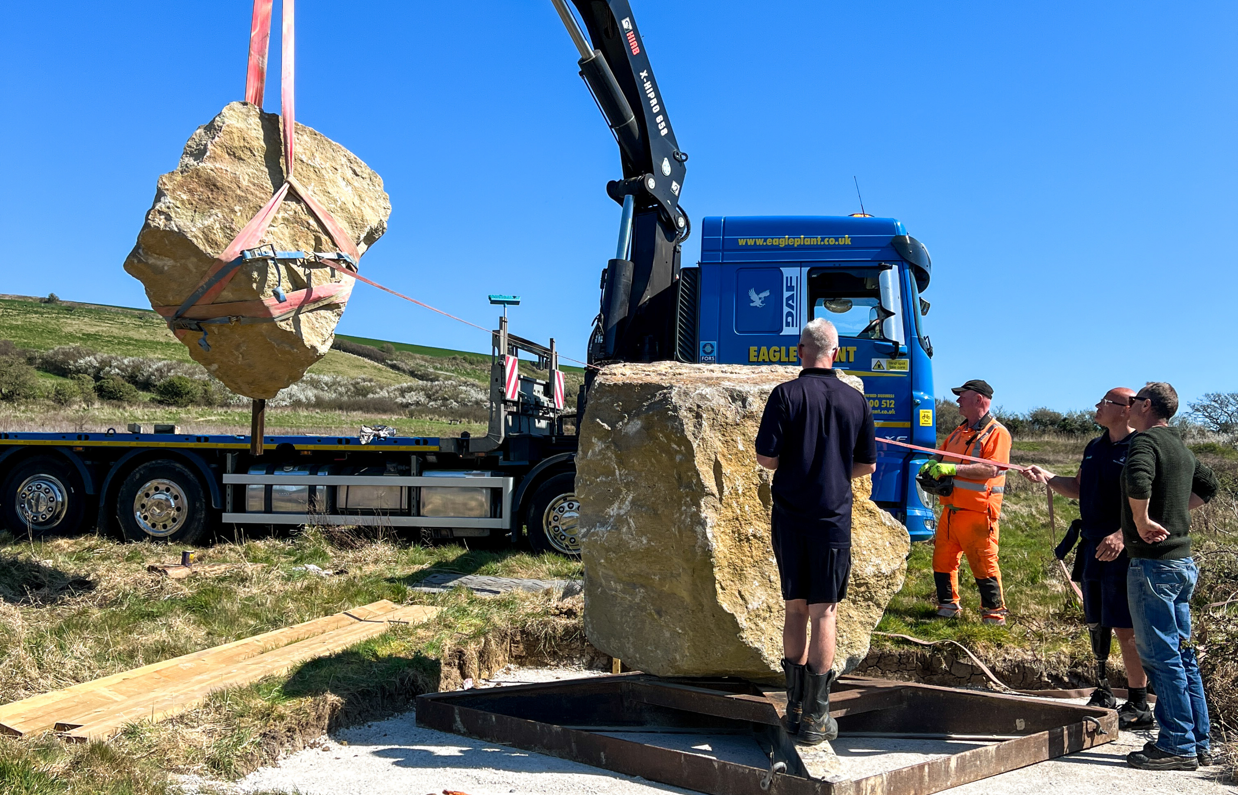 Installation of a stone sculpture in a field with blue skies