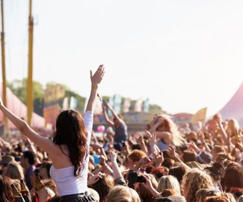 A festival crowd with people on shoulders with their arms in the air