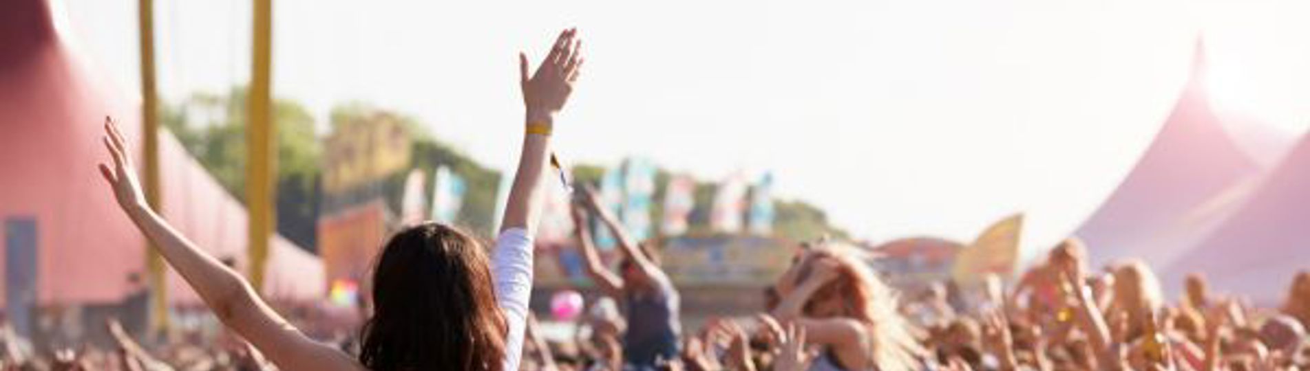 A festival crowd with people on shoulders with their arms in the air