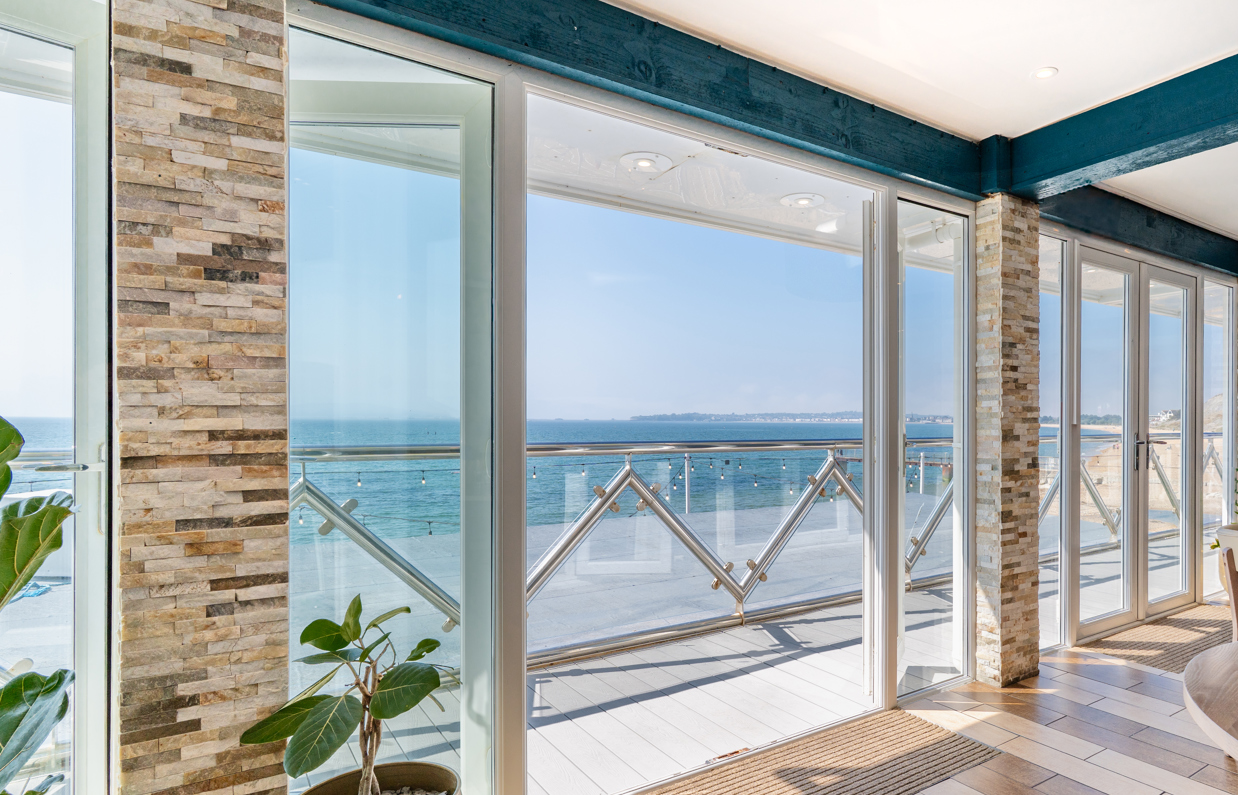 Views out to sea from Drift Bar & Grill's seating area through wide open french doors on a sunny, blue sky day