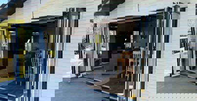 Bi-fold patio doors open onto decking with view back into lodge