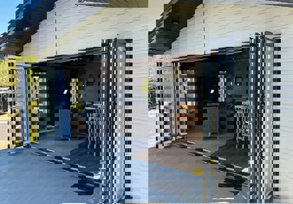 Bi-fold patio doors open onto decking with view back into lodge