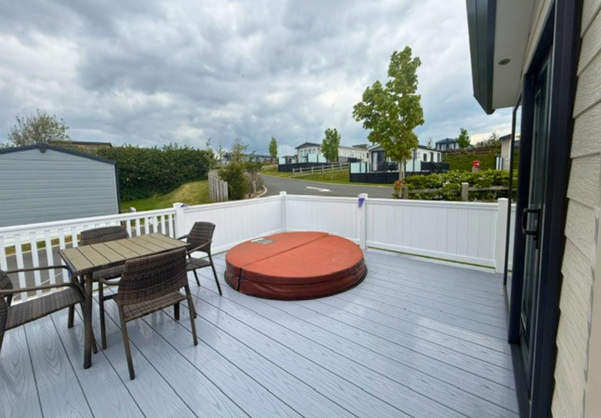 External of a caravan with decking, hot tub and table & chairs