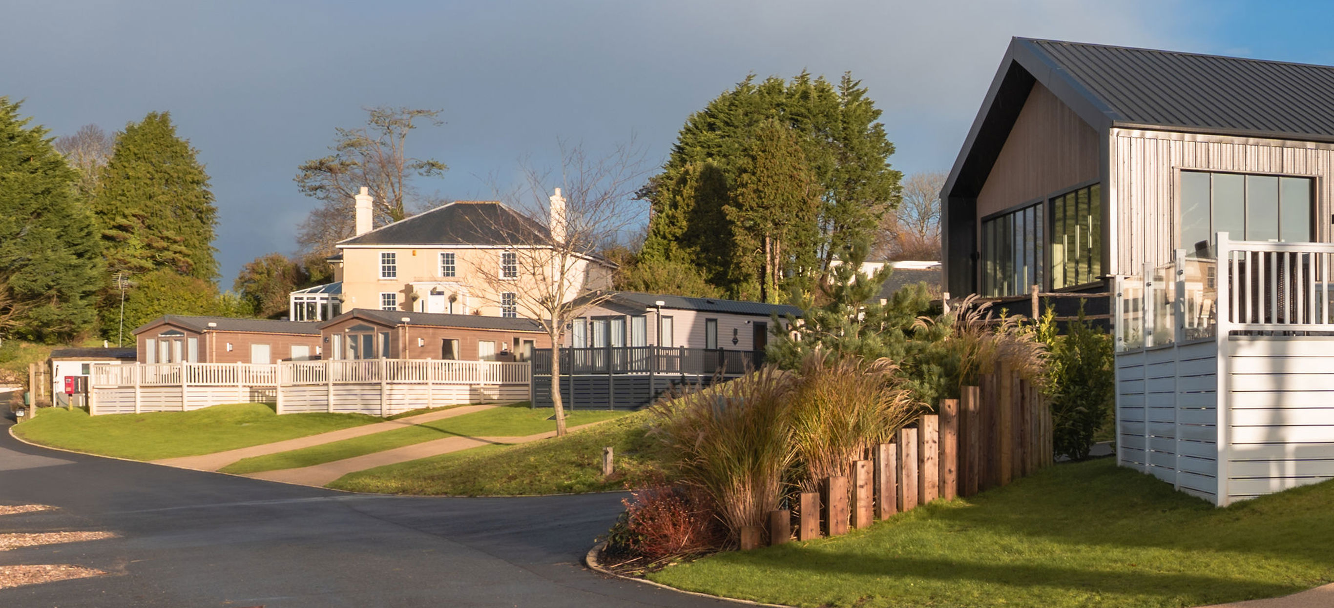 View of the Manor House and The Barn with a few caravans in front with cloudy moody skies