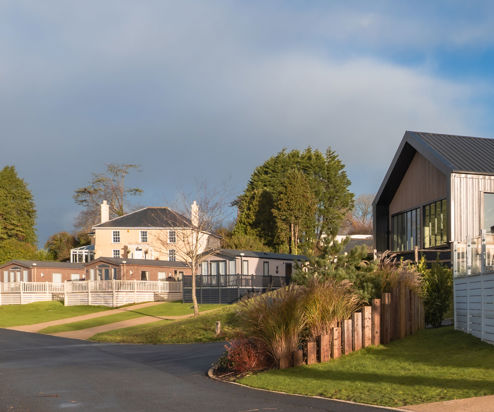 View of the Manor House and The Barn with a few caravans in front with cloudy moody skies