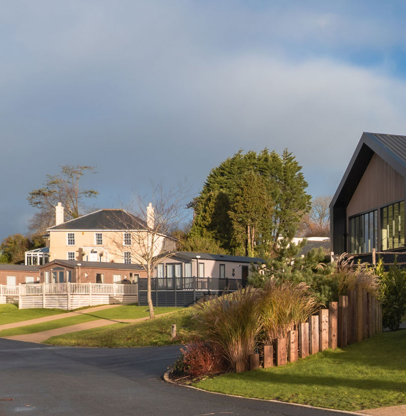 View of the Manor House and The Barn with a few caravans in front with cloudy moody skies