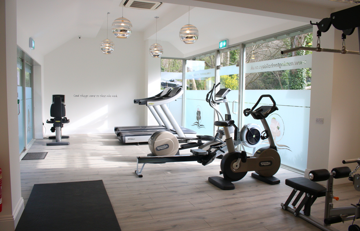 A Well-Lit Gym Among Countryside with Bikes, Treadmills, Rowing Machines and Weights