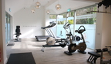 A Well-Lit Gym Among Countryside with Bikes, Treadmills, Rowing Machines and Weights