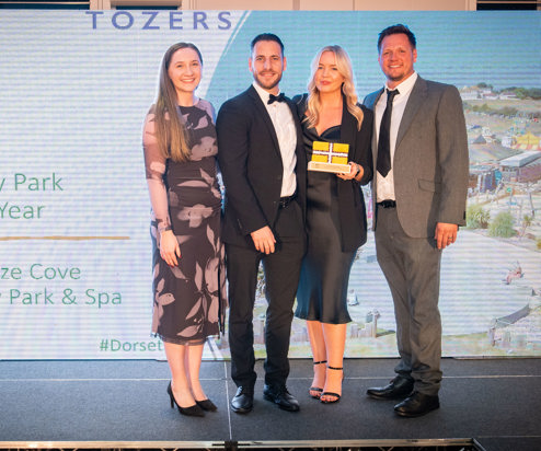 Four people stood smiling with an award