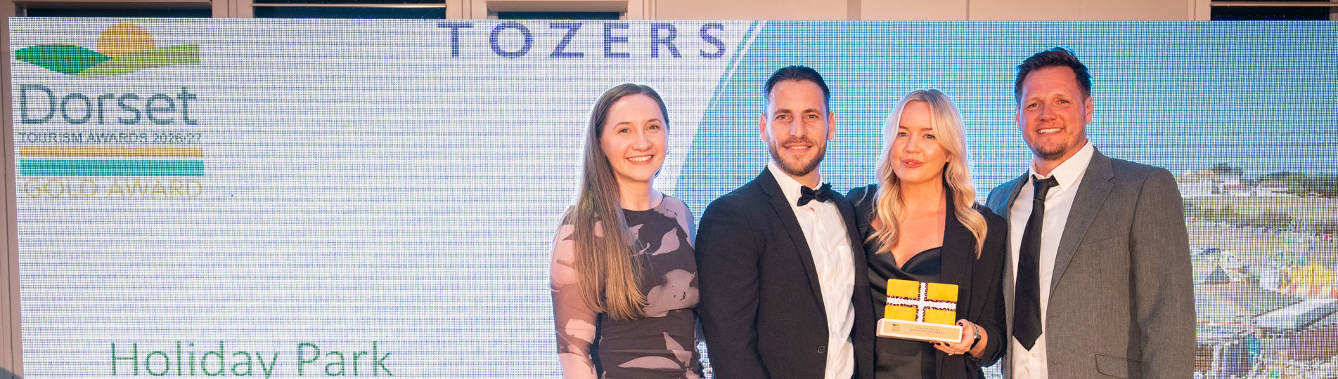 Four people stood smiling with an award