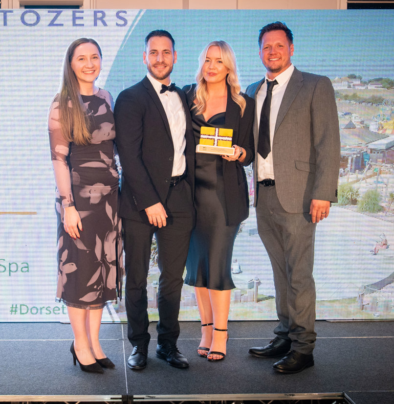 Four people stood smiling with an award