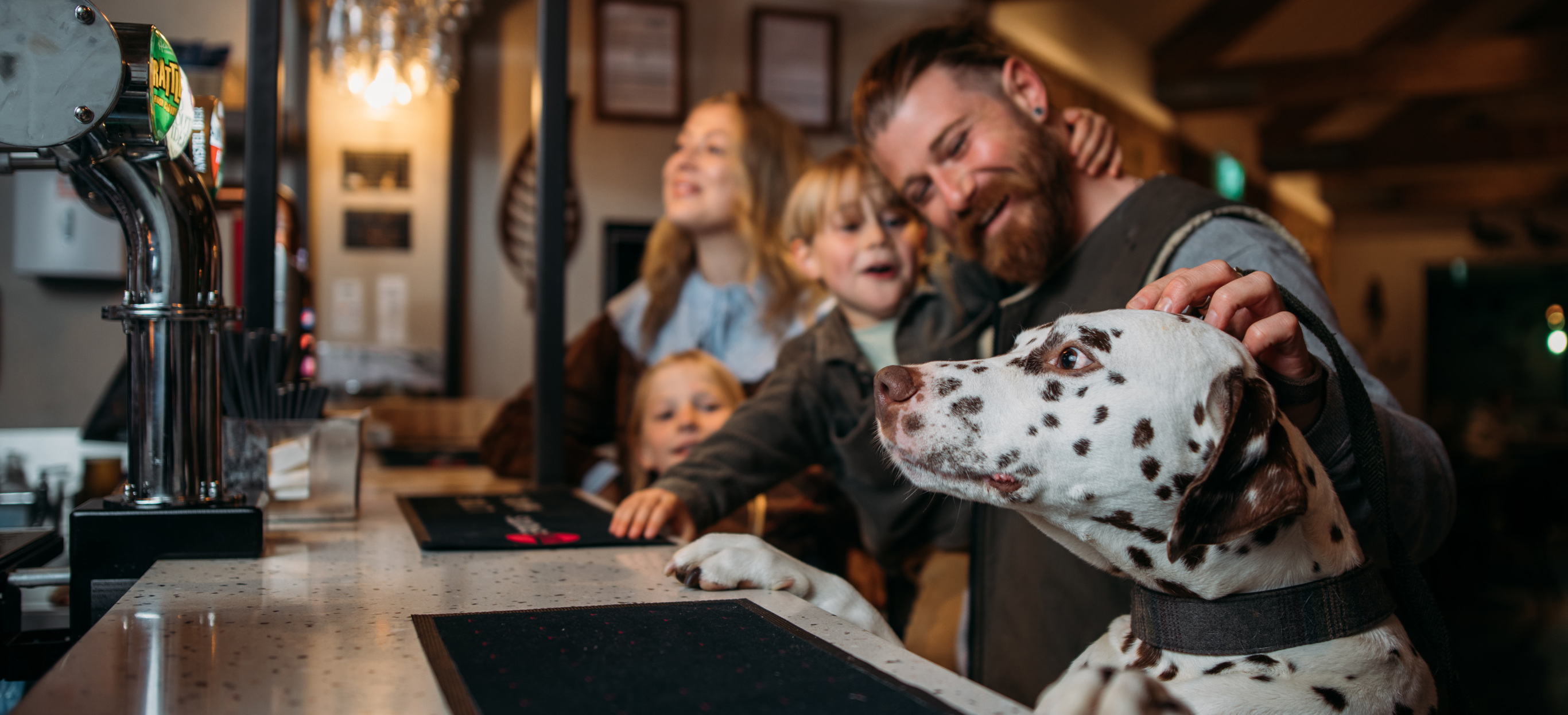 Dog with paws on bar while family order drinks