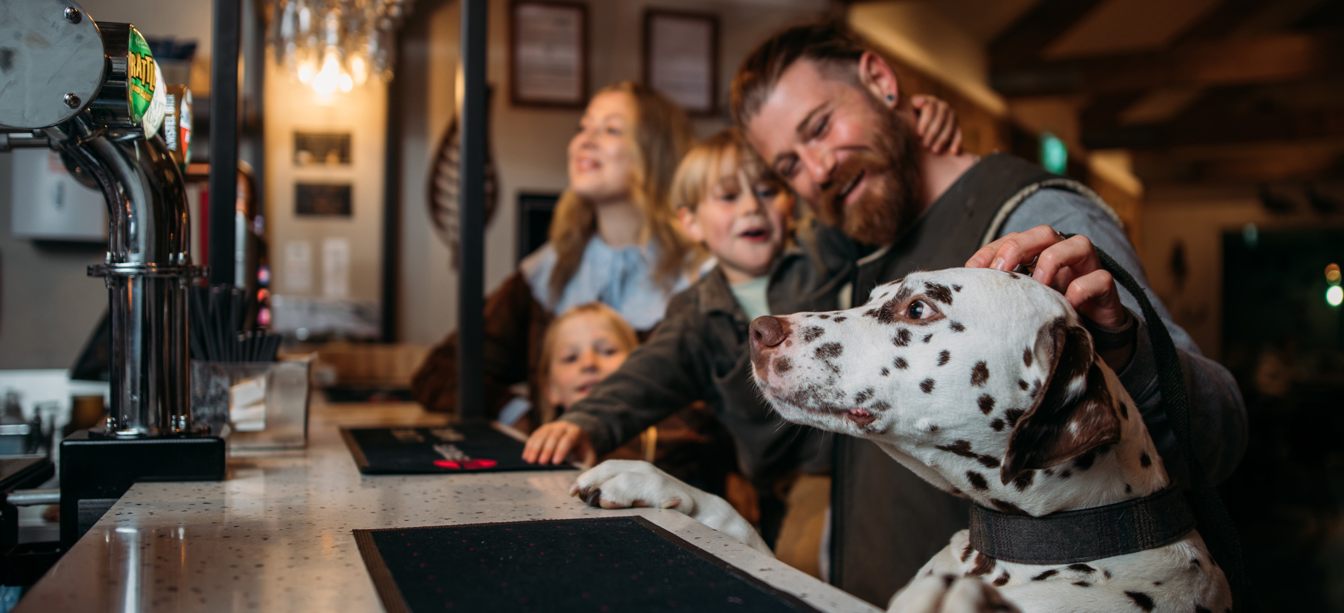 Dog with paws on bar while family order drinks