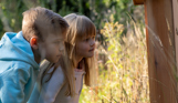 A young boy and girl looking for wildlife among woodland