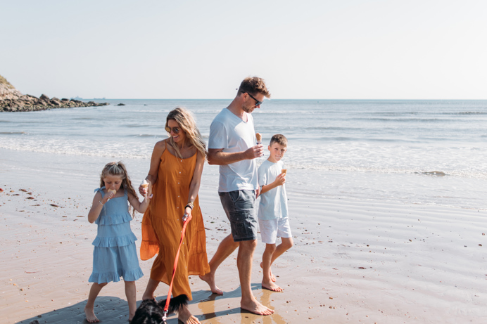 Family walking a dog on the beach eating ice creams