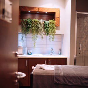 A spa treatment room with shower, bed, products and cosy, calming decór