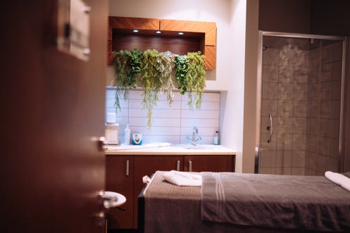 A spa treatment room with shower, bed, products and cosy, calming decór