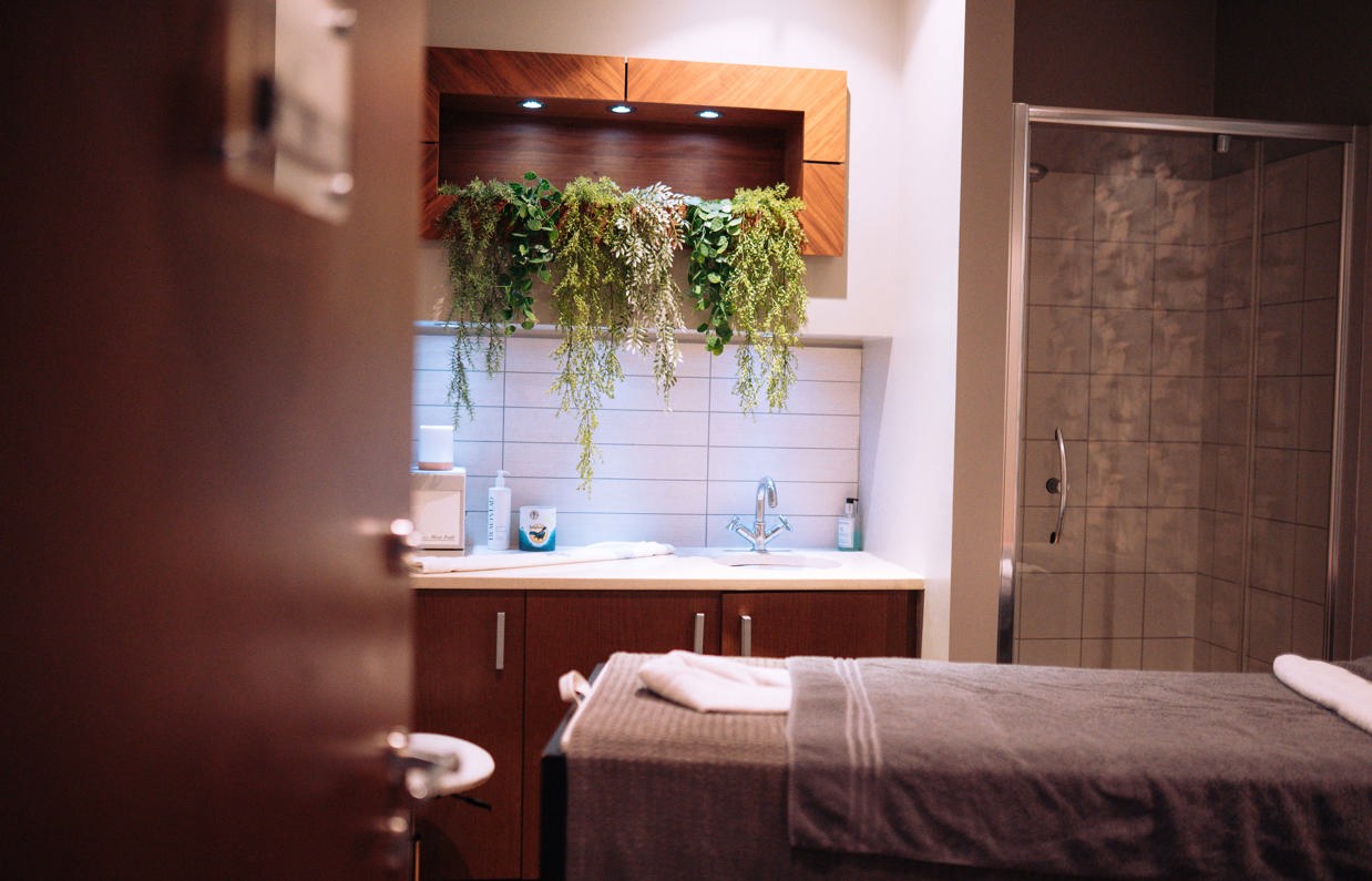 A spa treatment room with shower, bed, products and cosy, calming decór