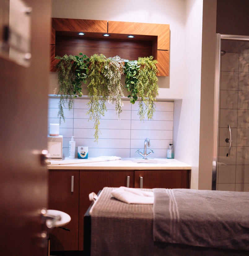 A spa treatment room with shower, bed, products and cosy, calming decór