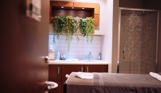 A spa treatment room with shower, bed, products and cosy, calming decór