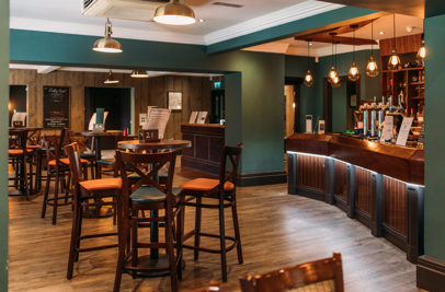 The inside of The Country Club with high tables and chairs and a bar with dramatic lighting
