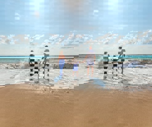 A family of three on the beach on a sunny day in the water