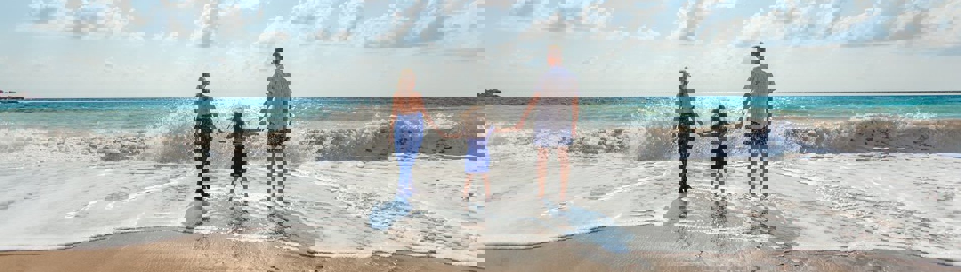 A family of three on the beach on a sunny day in the water