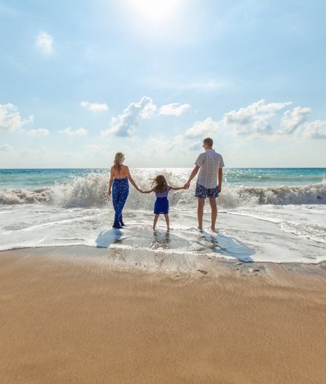 A family of three on the beach on a sunny day in the water