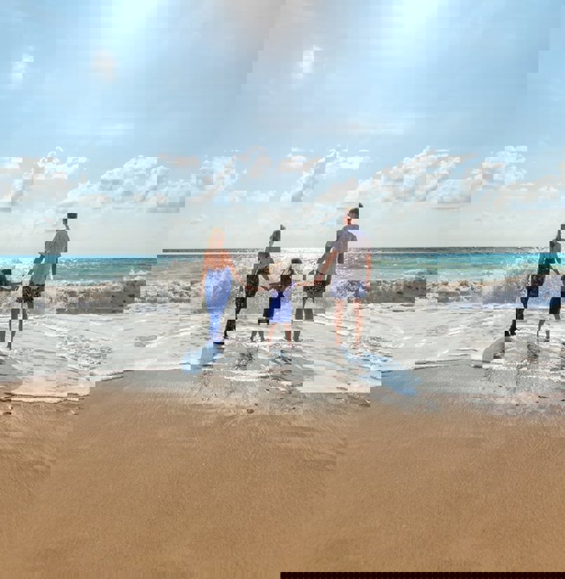 A family of three on the beach on a sunny day in the water