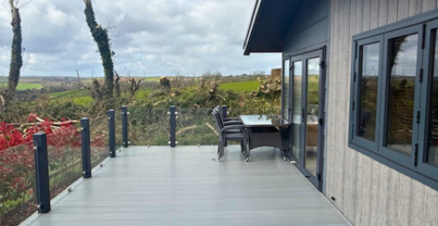 External of a lodge on pitch with decking, outdoor furniture and countryside views