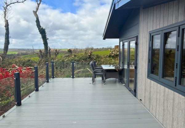 External of a lodge on pitch with decking, outdoor furniture and countryside views
