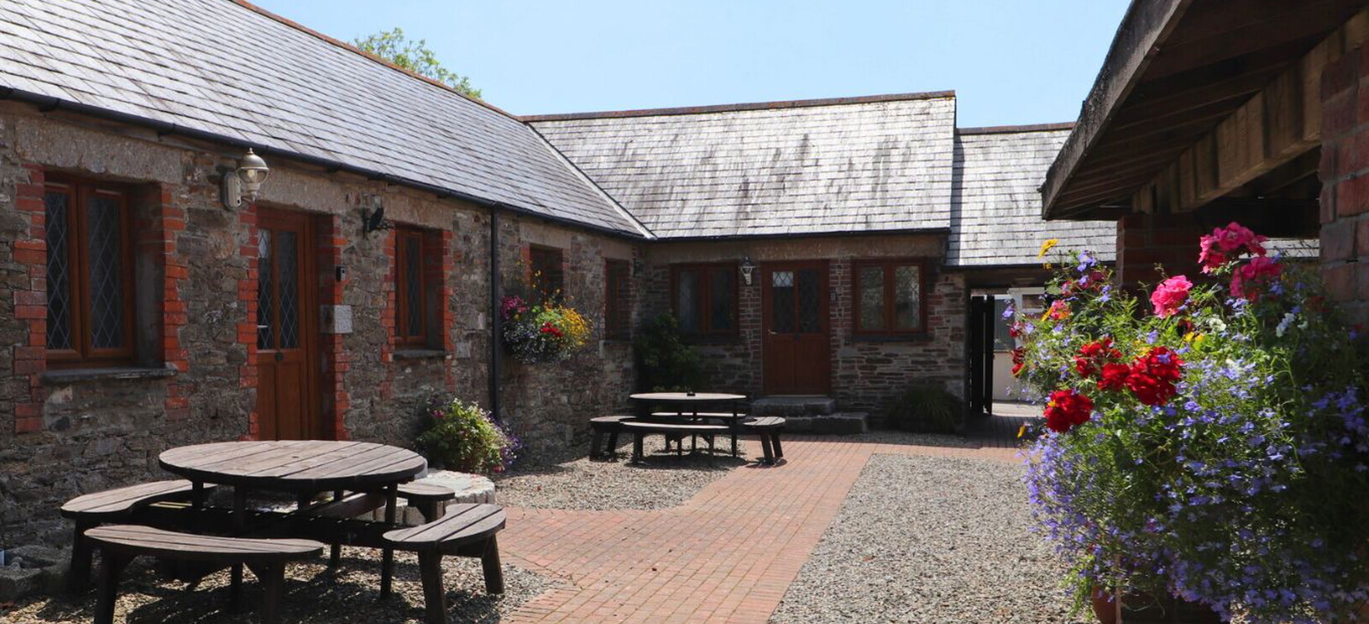 External of a cottage courtyard area with outdoor benches and flowers