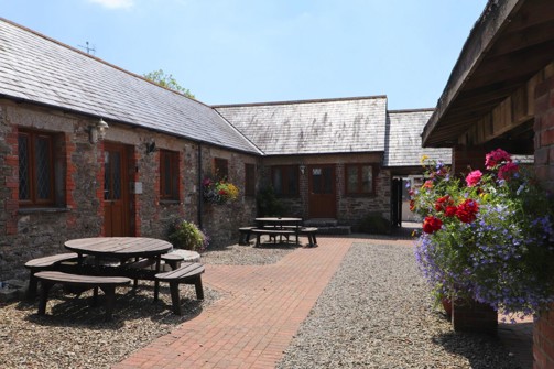 External of a cottage courtyard area with outdoor benches and flowers