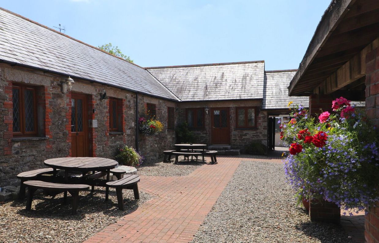 External of a cottage courtyard area with outdoor benches and flowers
