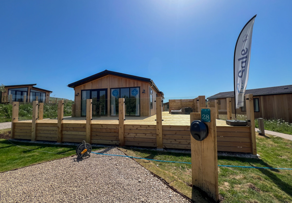 External of a luxury lodge on pitch with decking and hot tub