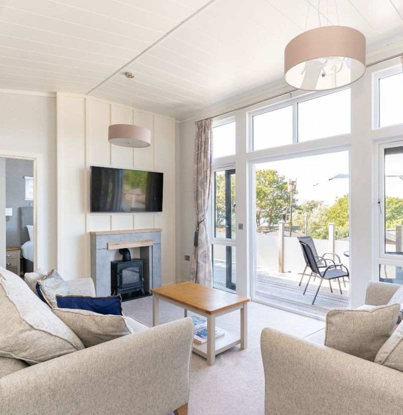Internal of a lodge open plan lounge with doors out to decking with outdoor furniture and seaviews