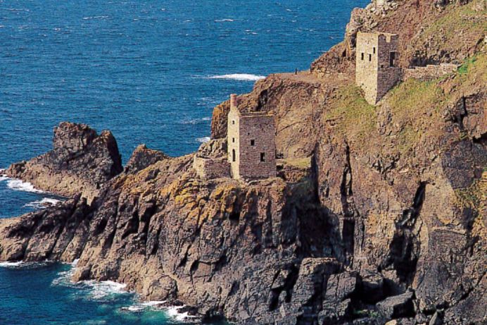 Old mine remains set into the rocky cliff face by the sea