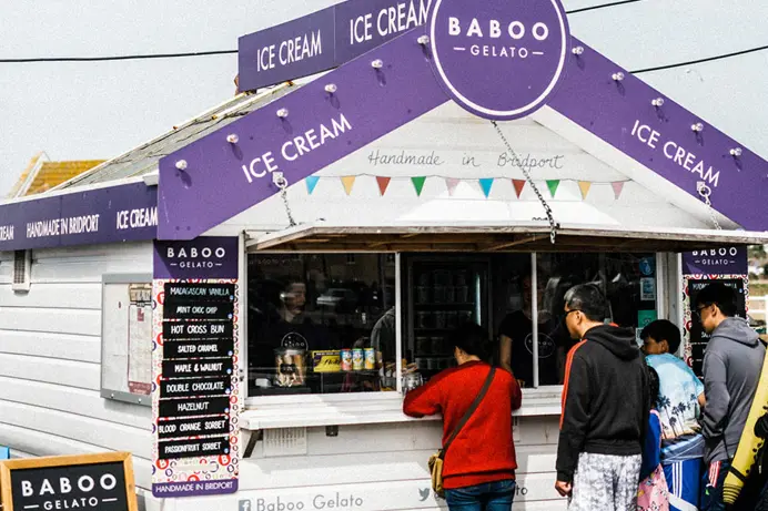 A wooden hut selling ice cream with a queue of people 