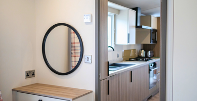 Internal of a caravan double bedroom with dressing area adjacent to kitchen