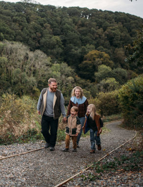A family of four walking along a nature path among woodland 