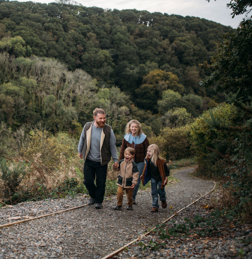 A family of four walking along a nature path among woodland 