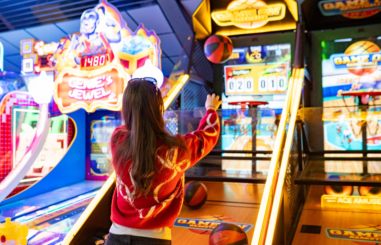 A girl throwing a basketball at the hoop on an arcade basketball game