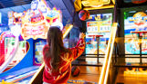 A girl throwing a basketball at the hoop on an arcade basketball game