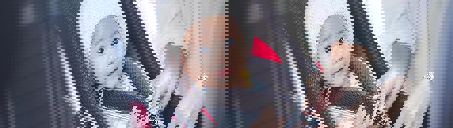 A young child in a car seat being strapped in by a lady