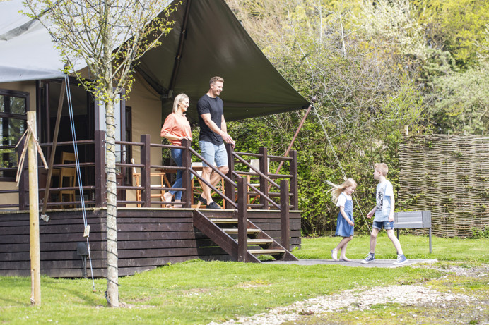 A family of four outside a safari lodge on Bowleaze Cove Holiday Park & Spa